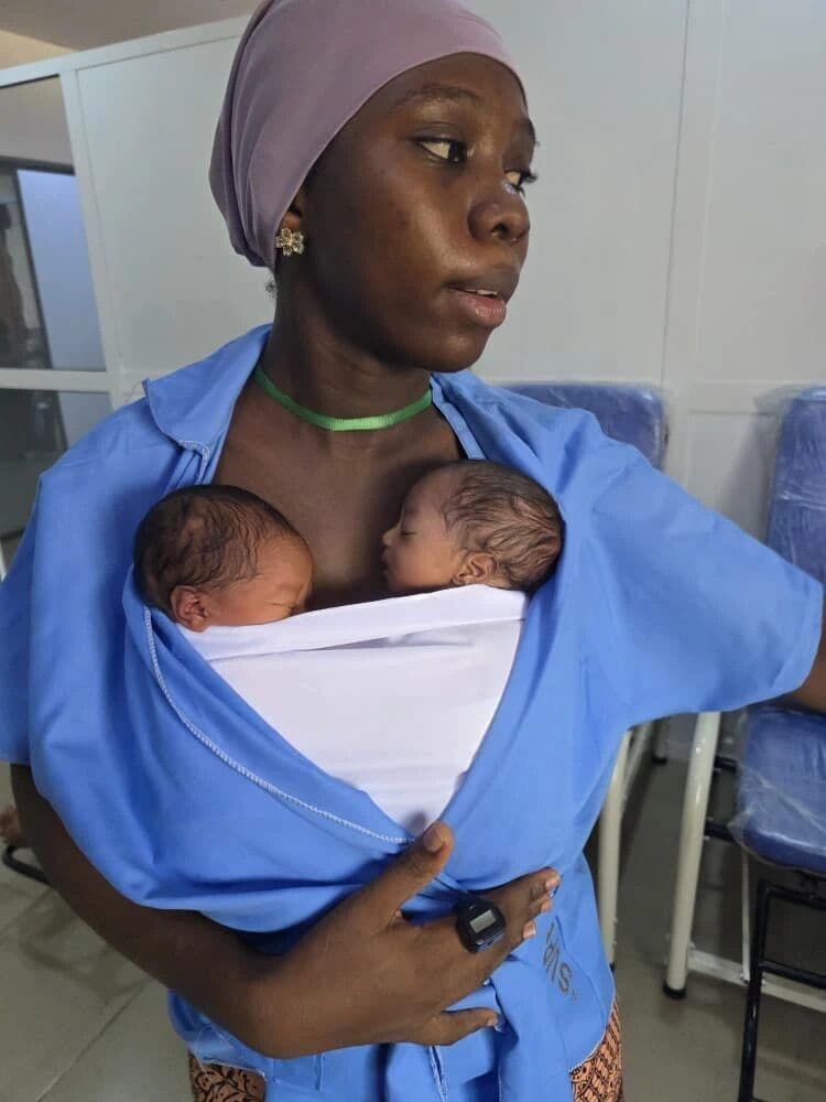 A mother in a Kangaroo Care gown holding her newborn twins skin-to-skin