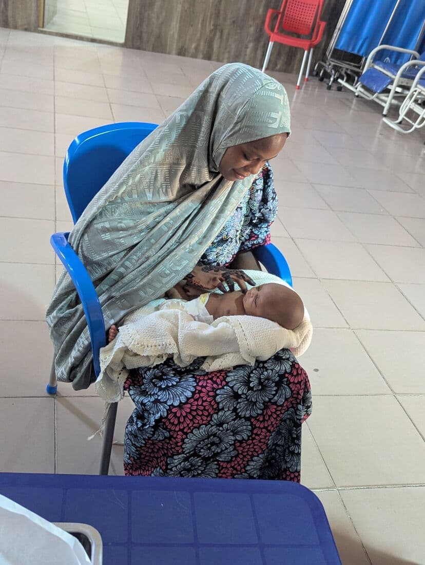 A mother looking down at her newborn asleep on her lap