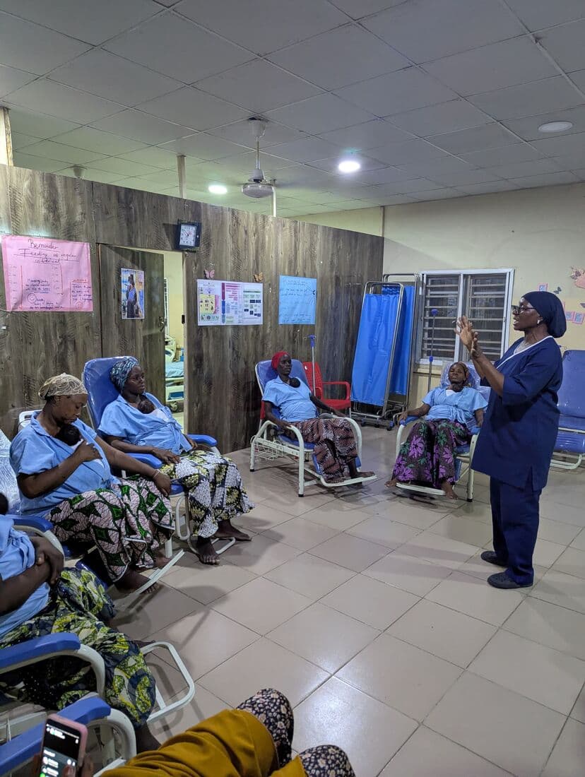 A nurse taking the ward's Kangaroo Care teaching session, mothers listening from the chairs
